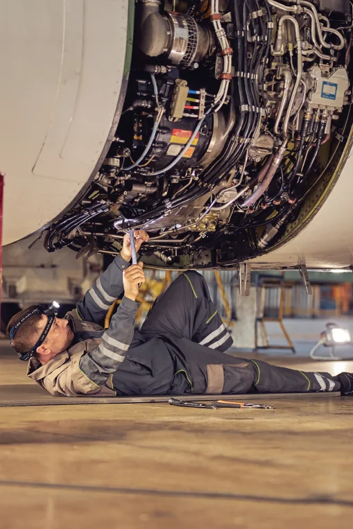 Aircraft maintenance technician working beneath an aircraft system