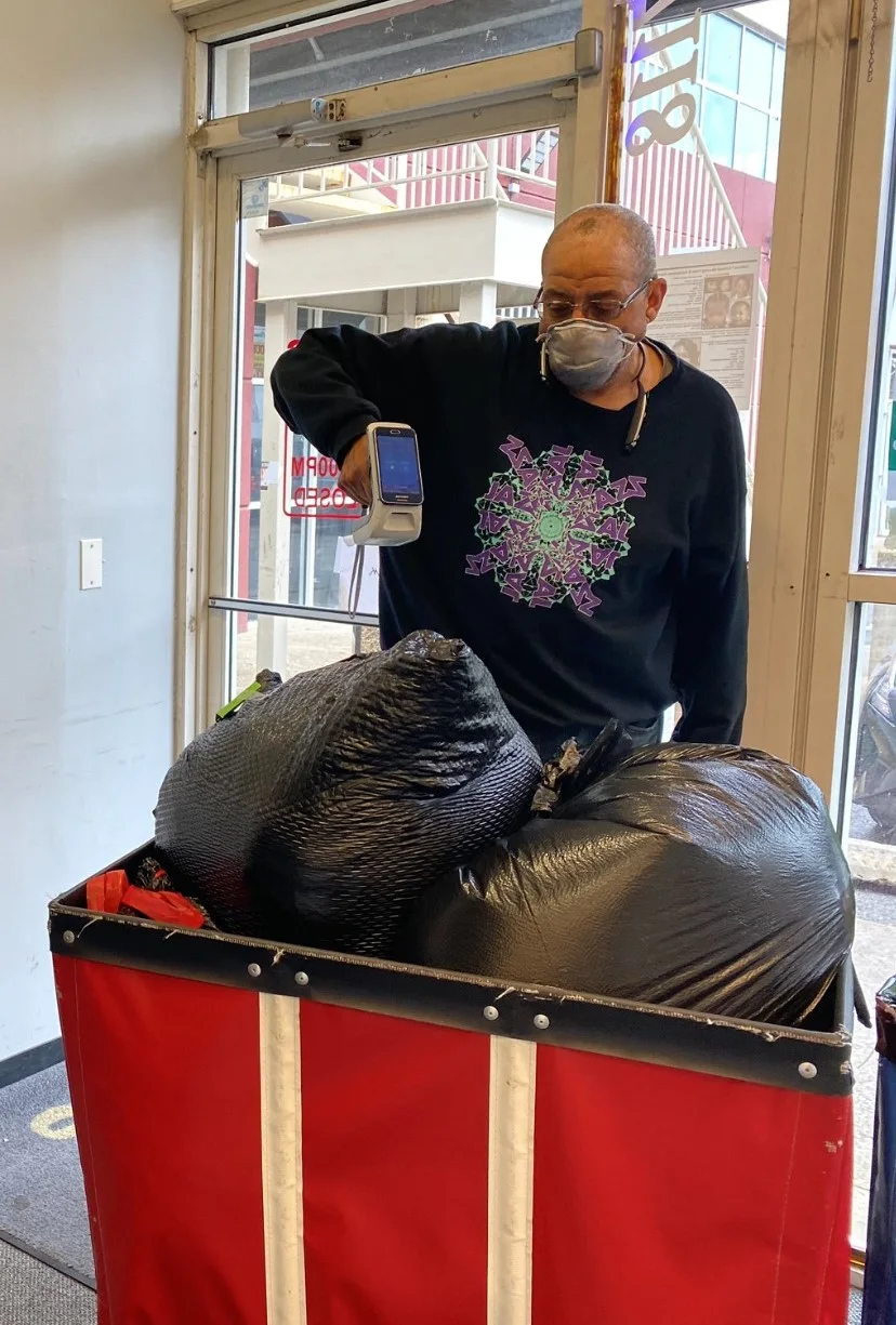 Laundry operator scanning a cart of bagged garments during a garment handoff