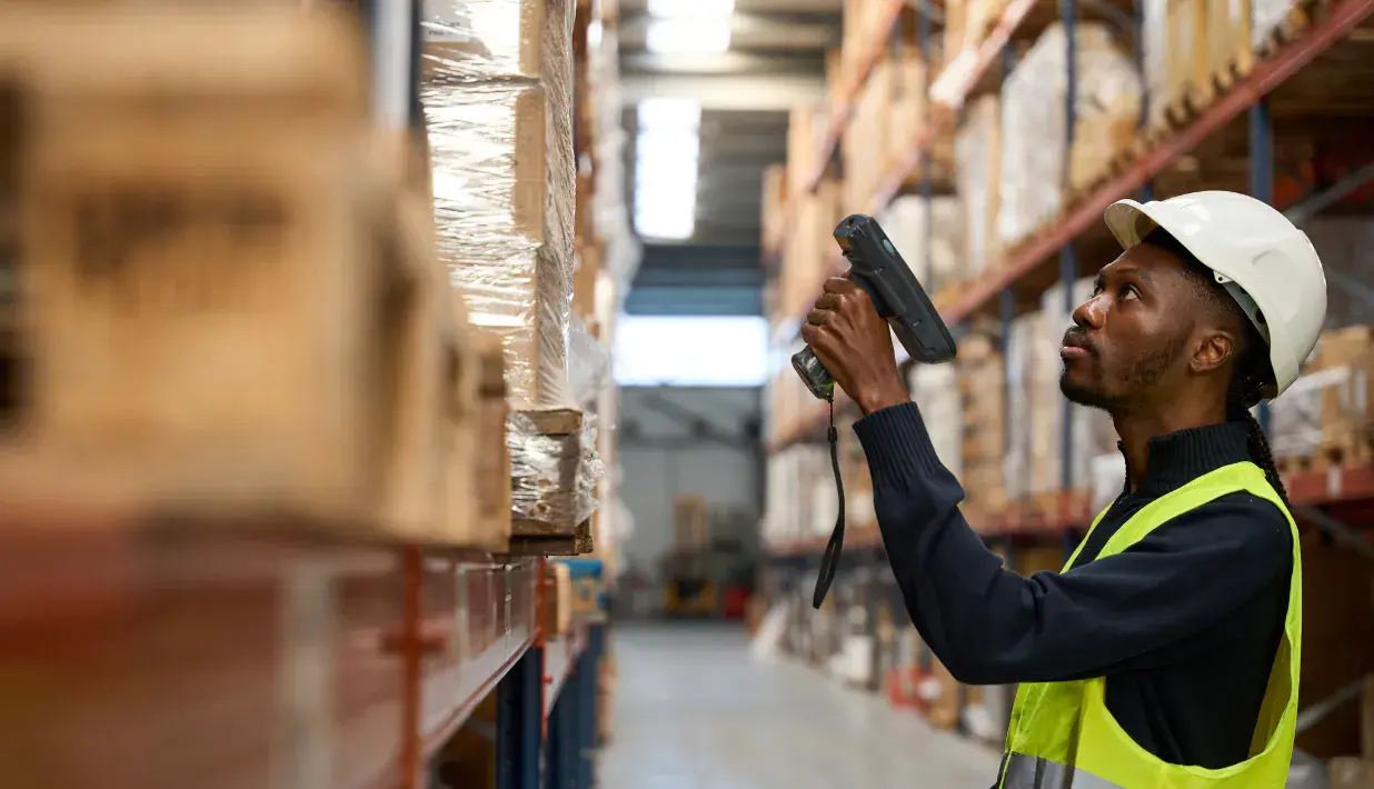 Warehouse worker using a handheld scanner beside storage racks
