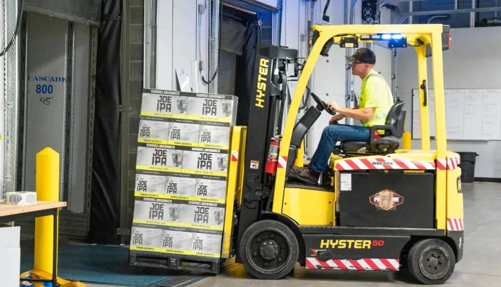 Forklift operator transports palletized goods while RFID tags capture movement data synced to warehouse and planning systems