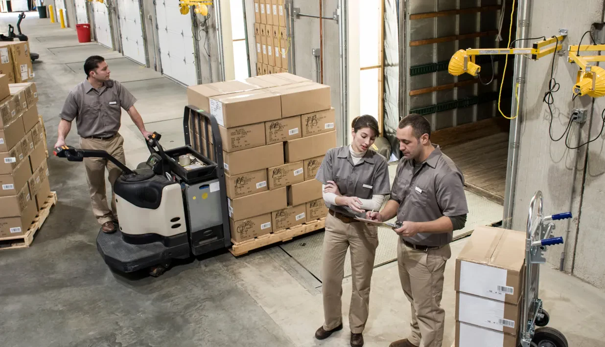 Warehouse receiving area with workers, cartons and a pallet truck
