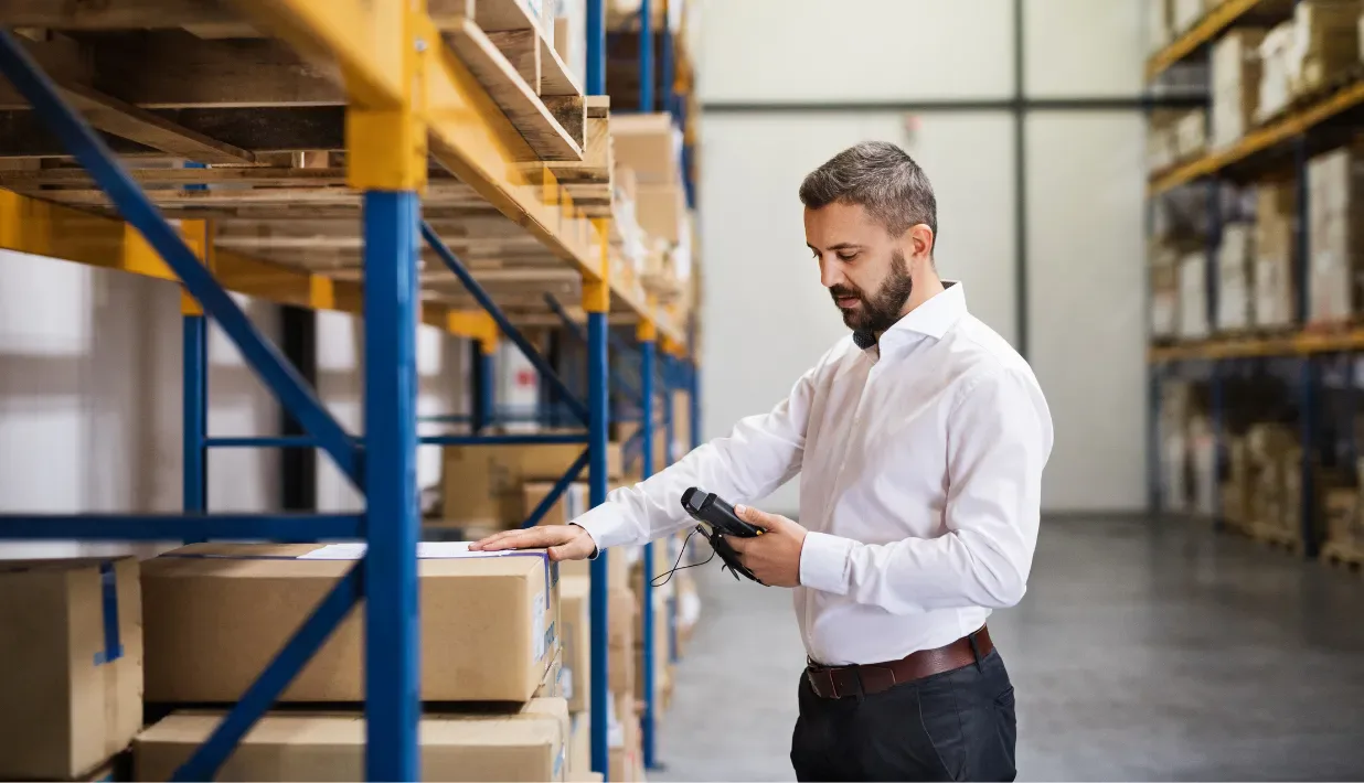 Warehouse worker reviewing cartons with an unbranded handheld device